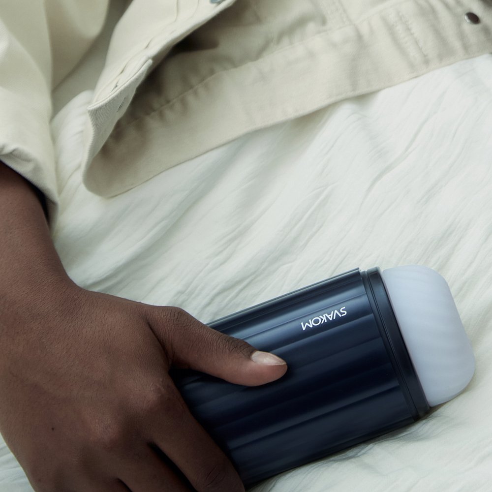 Hand Holding Svakom Sam Neo 2 Pro Interactive Heating, Sucking & Vibrating Masturbator On White Linen