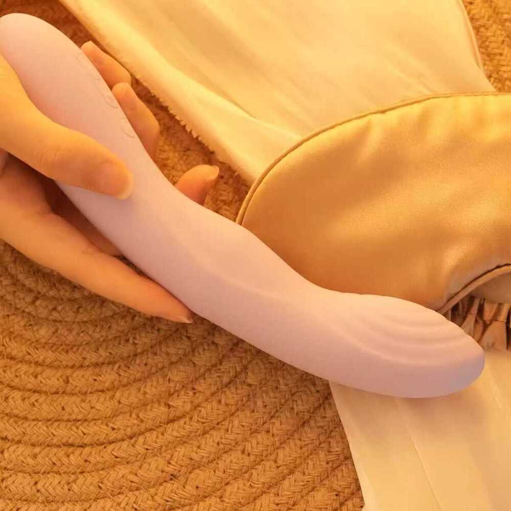 Person holding the Svakom Selena App-Controlled Heating & Thrusting G-Spot Vibrator next to a sleeping mask on a woven mat