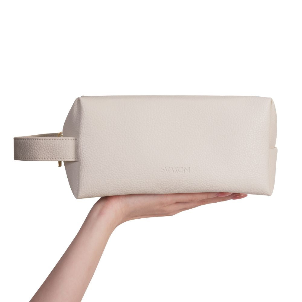 Svakom | Vegan Leather Storage Bag with Carry Handle (Beige) in hand, featuring the embossed 'SVAKOM' logo on the front and structured rectangular shape on a plain white background