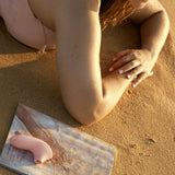 Pulse Lite Neo Interactive Suction Stimulator | Svakom (Pale Rosette) lying next to woman on beach sand