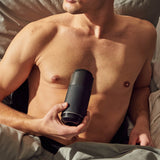 Man lying in bed with the Arcwave | Pow Stroker with Suction Control (Black) in hand