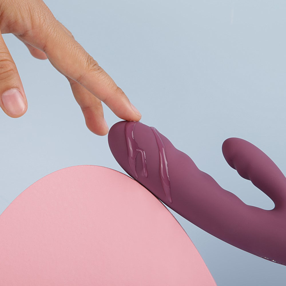 Hand Touching Avery Thrusting Rabbit Vibrator | Svakom - Lilac Dripping With Lube On Blue Background
