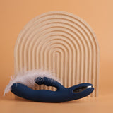 Aylin Powerful Pulsating Dual-Headed Rabbit Vibrator | Svakom (Dark Blue) with white feather and wooden backdrop