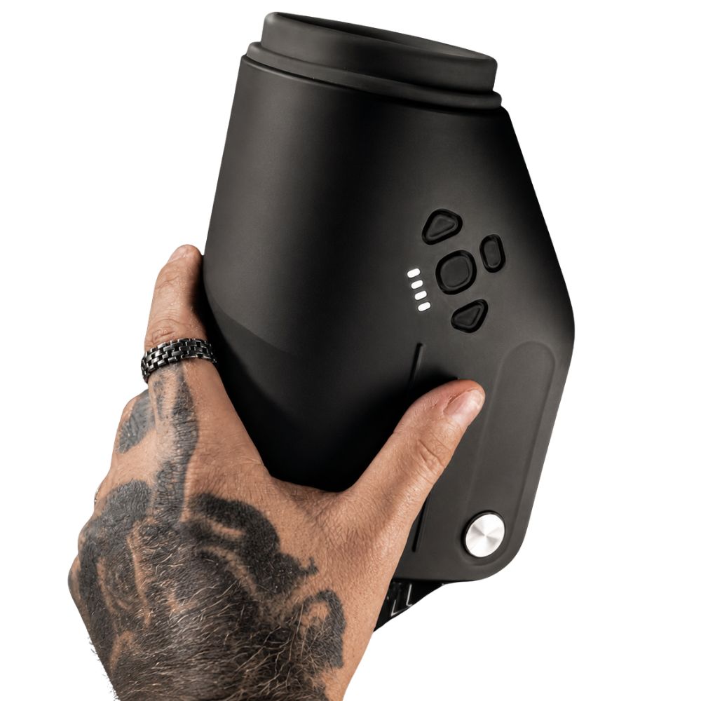 Kaotik Labs The Shotty Interactive Spinning, Thrusting & Vibrating Masturbator held in one hand on a white background, showing the black body, control buttons and battery indicator