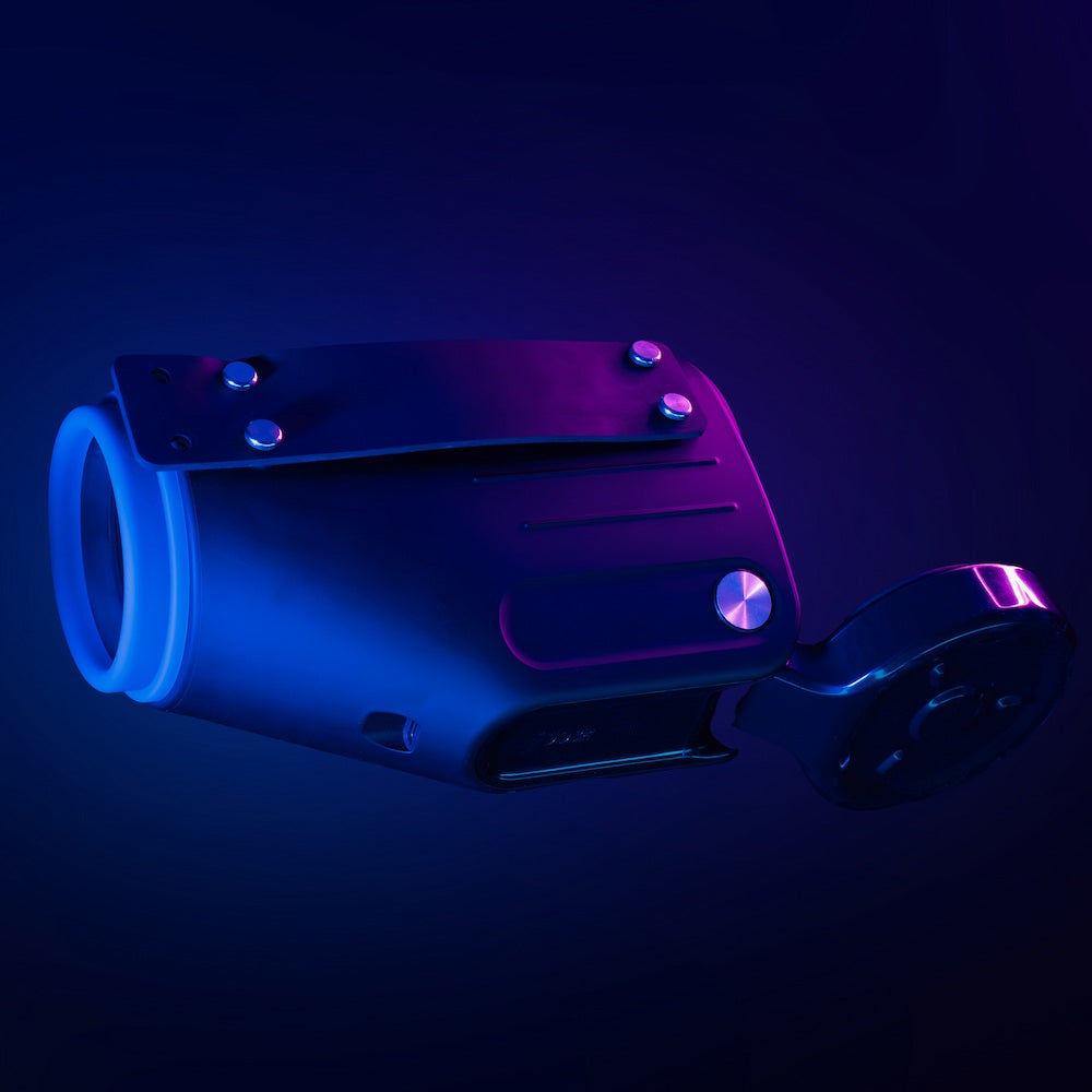 Side view of Kaotik Labs The Shotty Interactive Spinning, Thrusting & Vibrating Masturbator under blue and pink lighting, showing the rear strap and hinged base attachment.