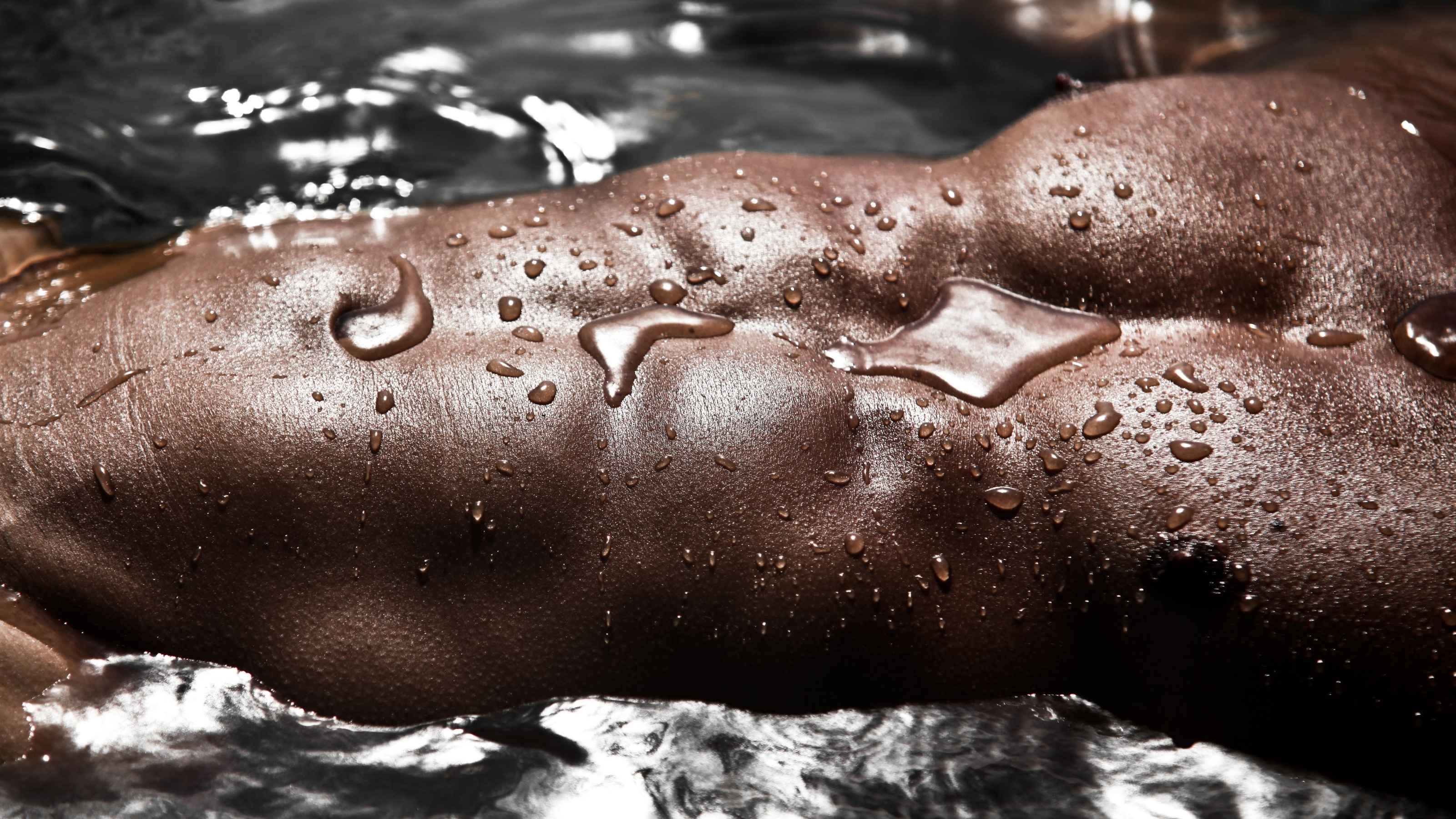 Close-up of a topless man's abs lying in water for Maysturbation | OneNightOnly