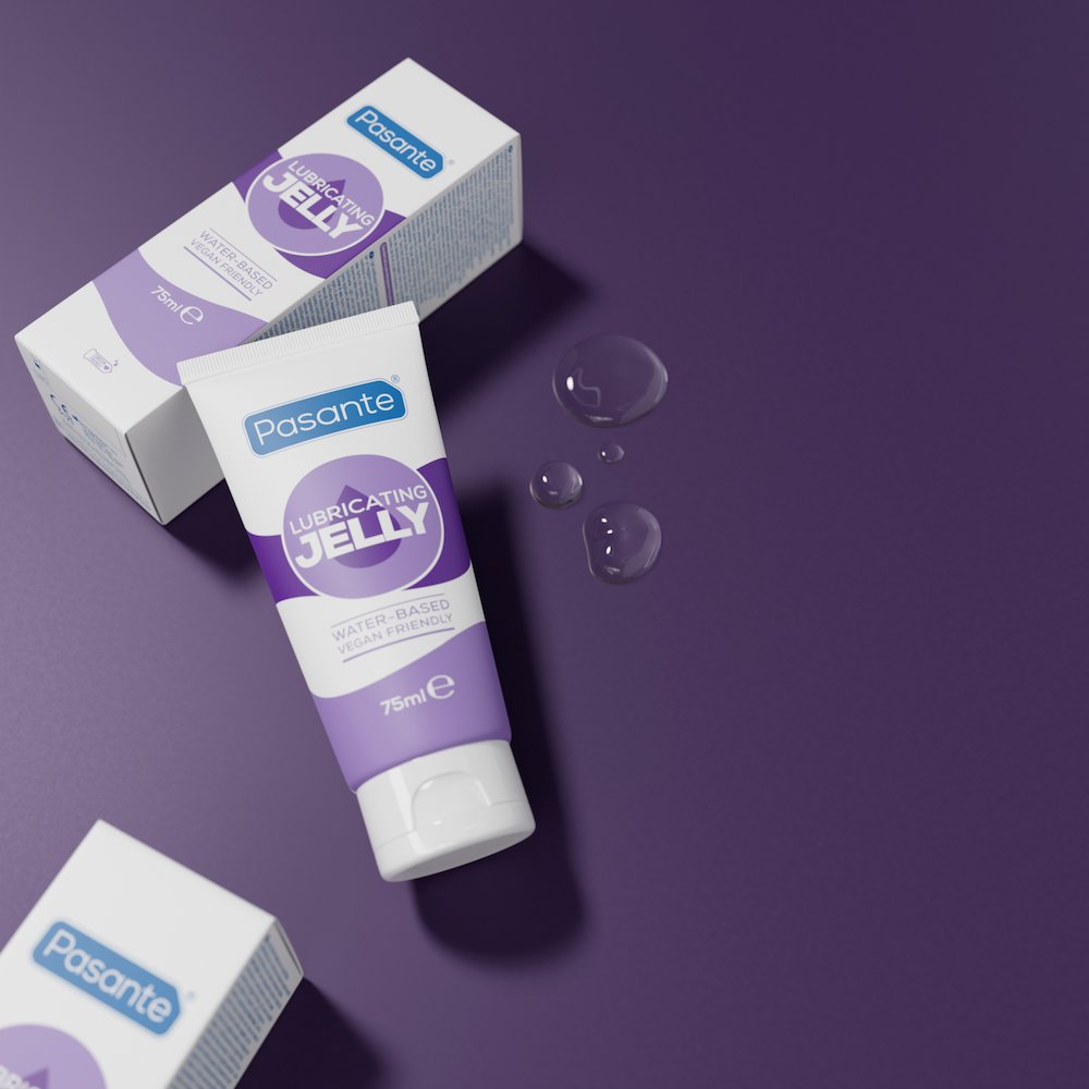 Pasante Lubricating Water-Based Jelly on a purple surface, leaning against its box, with small lube droplets beside the tube