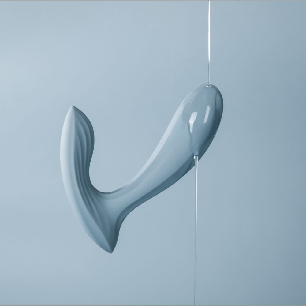 Lube being poured over Svakom | Erica App-Controlled Wearable Vibrator & Anal Stimulator (Dusty Blue) on blue background