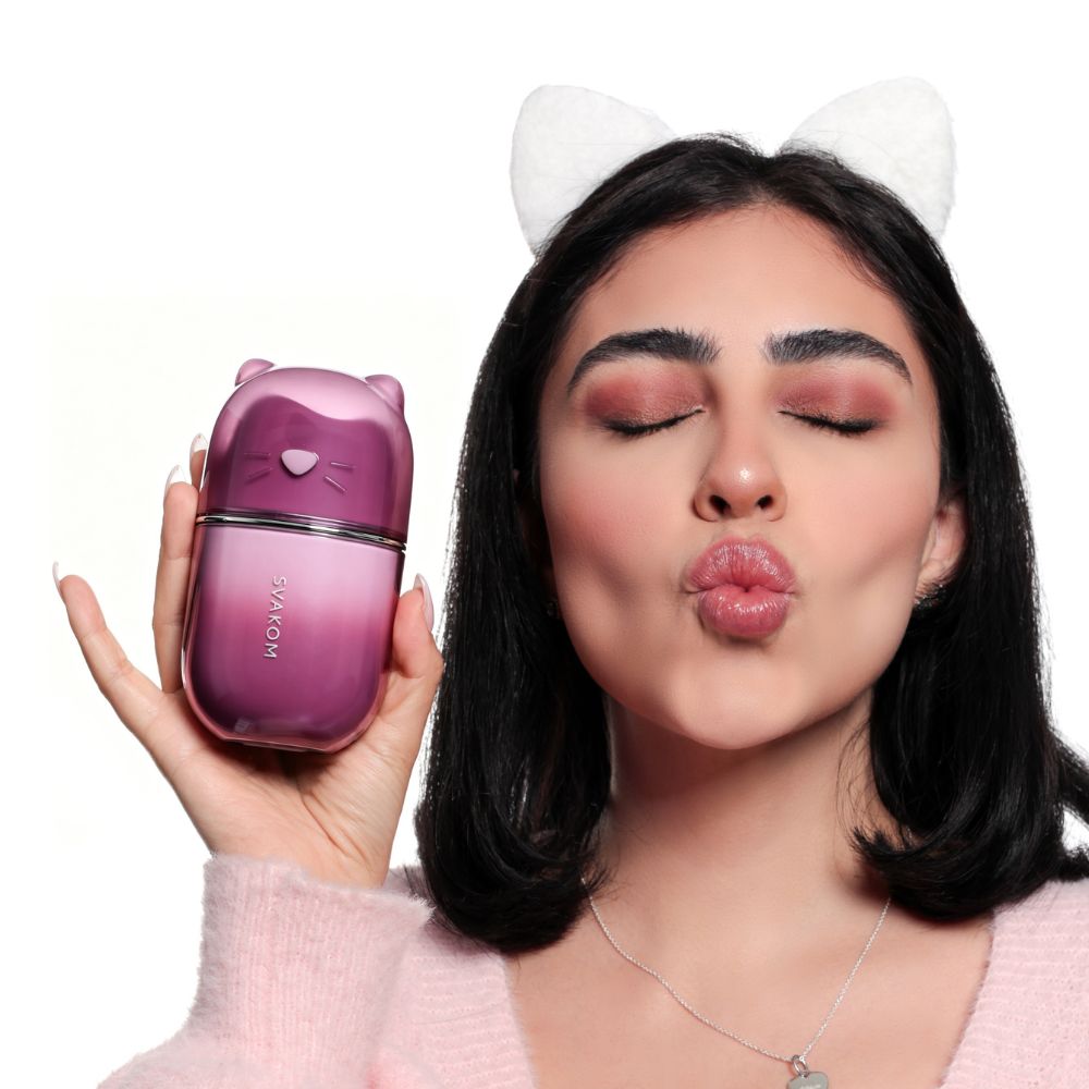Woman holding the Svakom Klitty Interactive Licking, Sucking & Vibrating Clitoral Stimulator beside her face, highlighting the compact cat-inspired design.