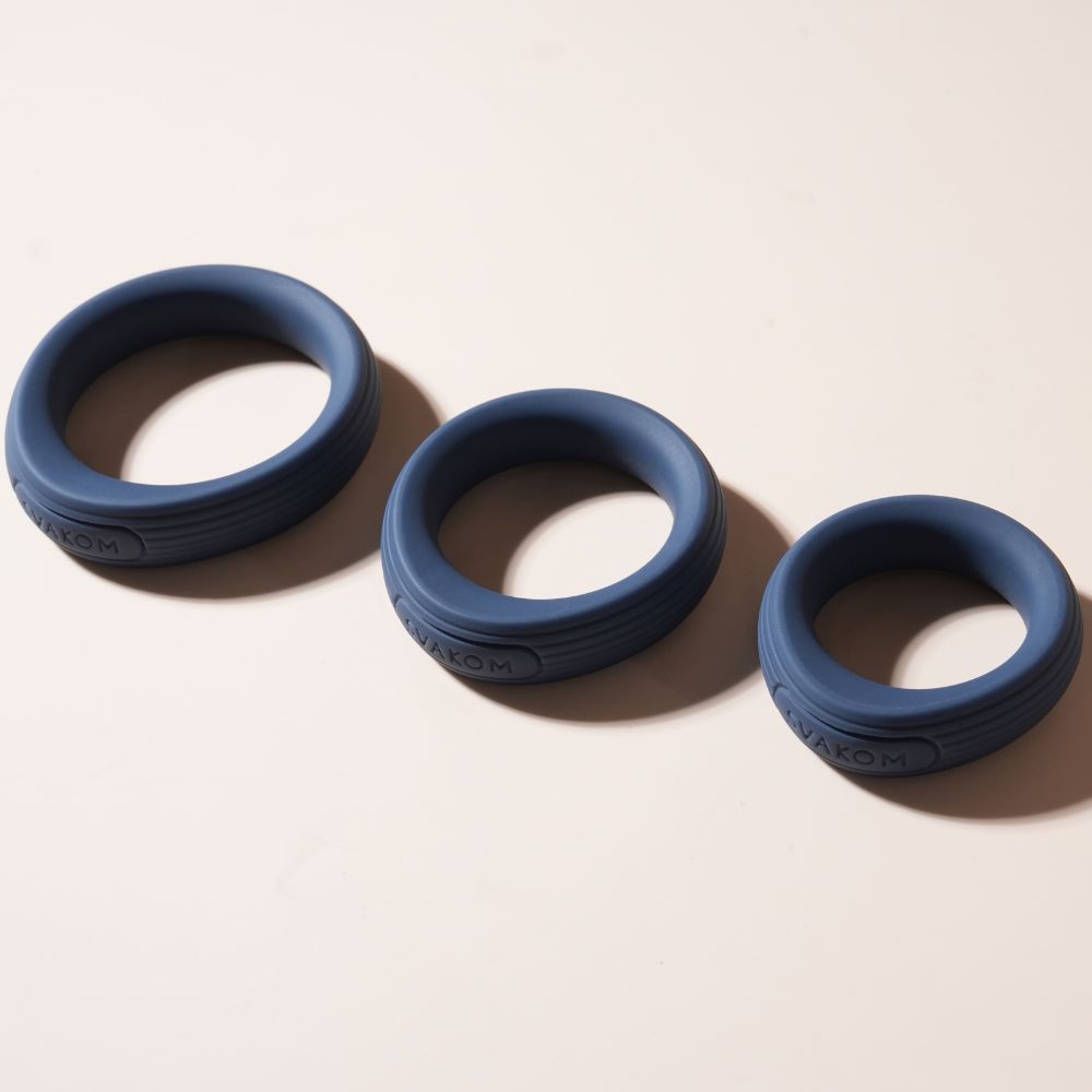 Svakom Triooo Three-Piece Silicone Cock Ring Set showing three dark blue silicone rings arranged on a beige surface.