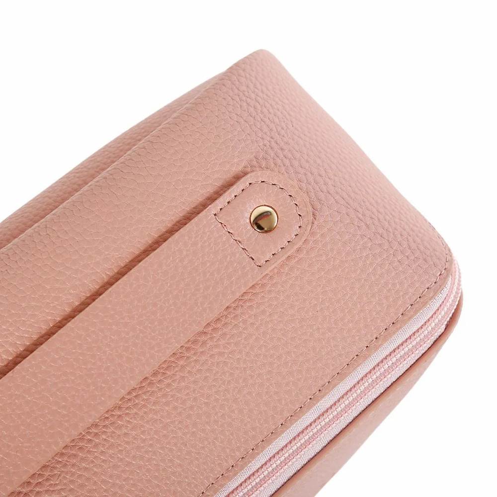 Close-up of the Womanizer Cosmetic Toy Bag in blush pink, showing the textured vegan leather finish, metal details and zip closure